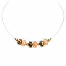 Cargar imagen en el visor de la galería, Illusion clear-cord choker with alternating beige and bronze-tone crystals on a white background