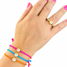 Cargar imagen en el visor de la galería, Marlene pink, blue and orange crystal cord bracelets worn on the wrist, with a gold-tone ring, against white