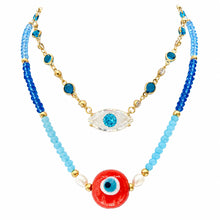 Cargar imagen en el visor de la galería, Look at Me blue crystal eye necklace layered with a blue beaded red-eye necklace on white